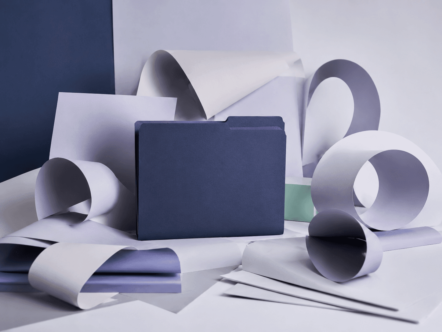 Folded pale paper forms curling into open spirals around one closed indigo folder